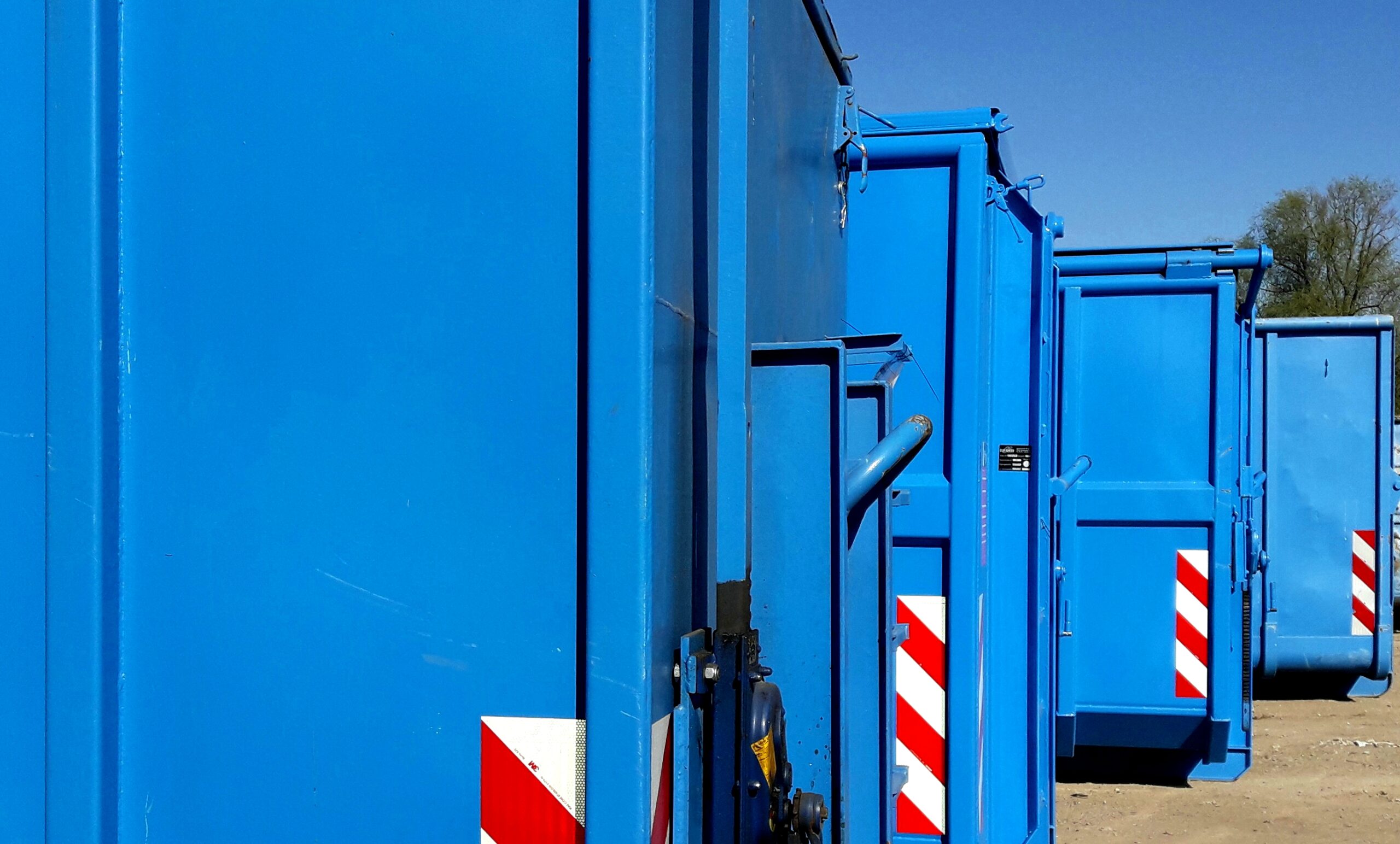 hintereinander aufgereihte blaue Abrollcontainer