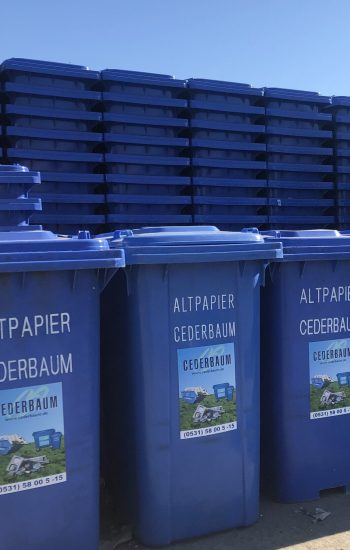 Mehrere Blaue Tonnen mit Cederbaum-Logo übereinander und hintereinander gestapelt